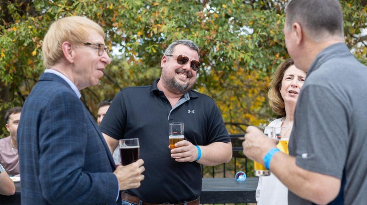 Alumni and faculty laugh and talk to each other.