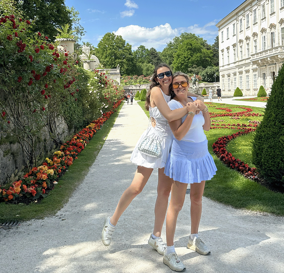 Two students smile in a garden of flowers.