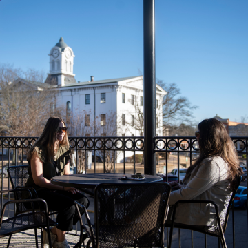 Two women sit on balcony of restaurant