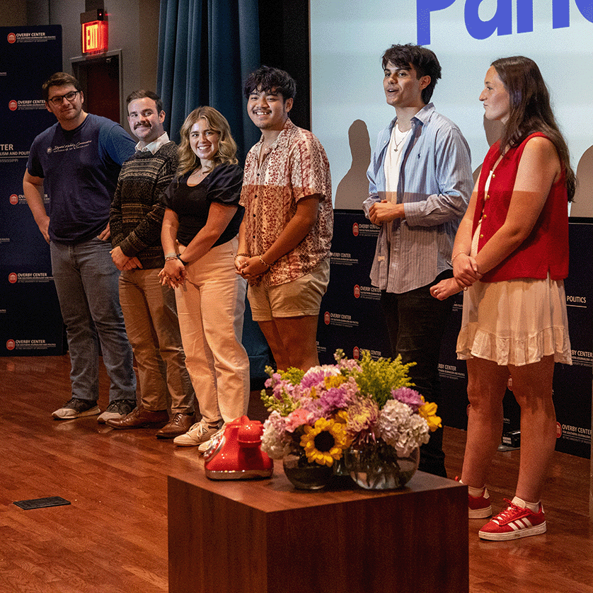 Six students stand infront of a screen and give a presentation.