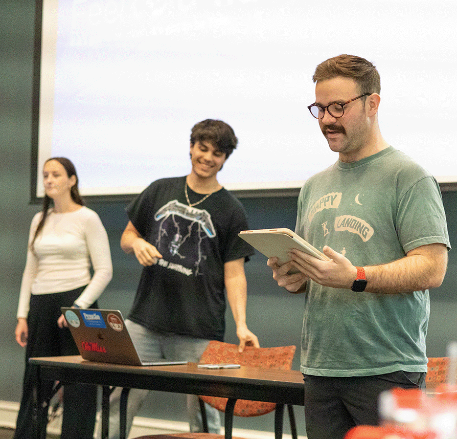 Student looks down at his notes as he gives a presentation.