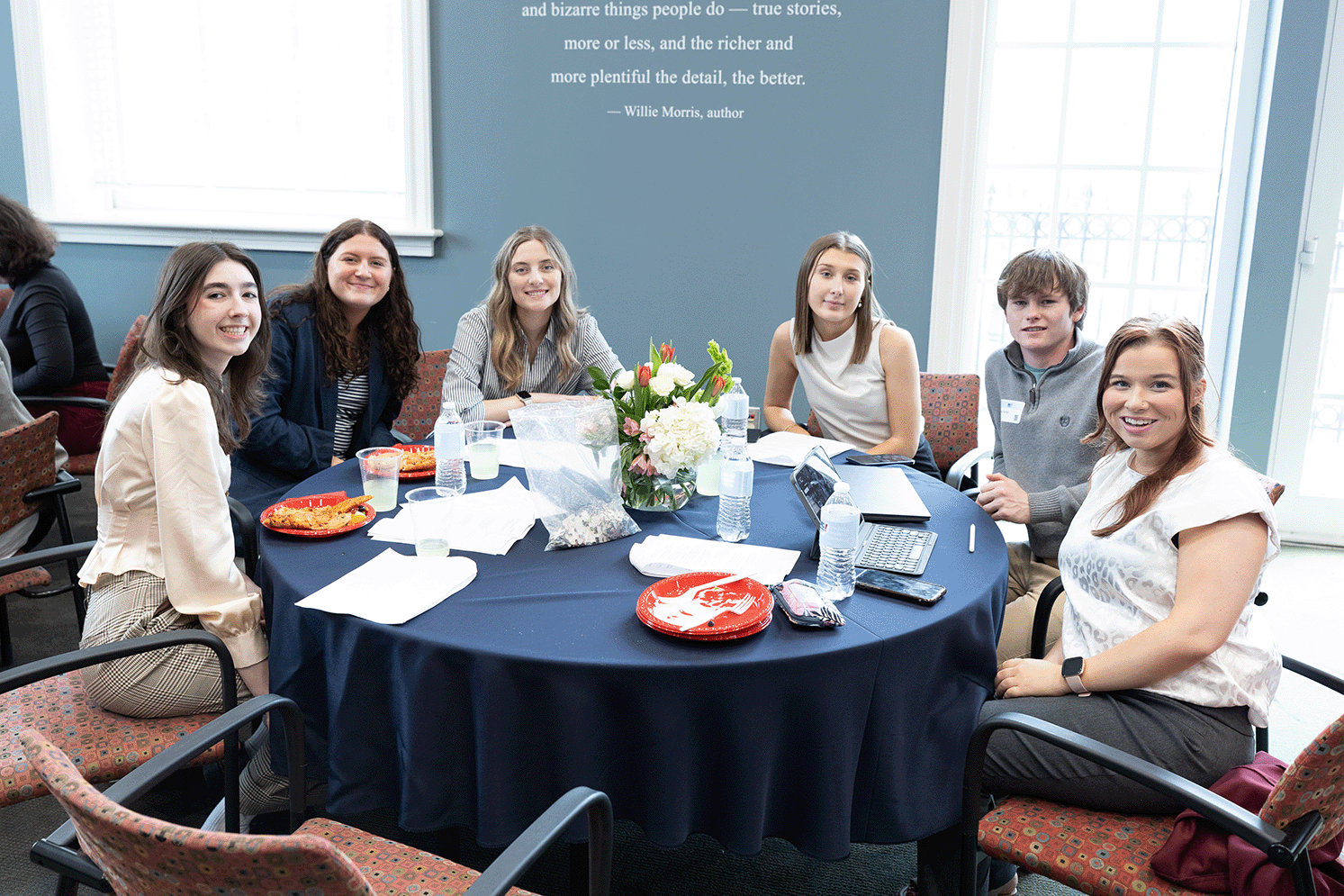 Students sit around a table and smile.