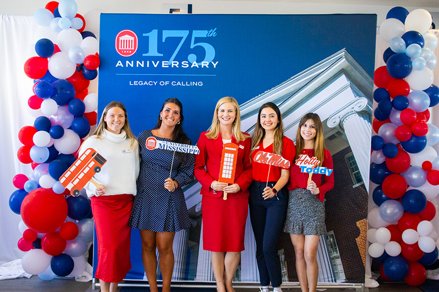 Students pose for a photo against a backdrop of The Lyceum that says "175th anniversary of the University of Mississippi".