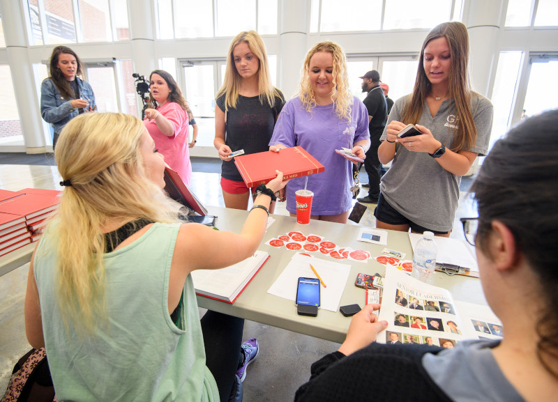 Students pass out yearbooks to others.