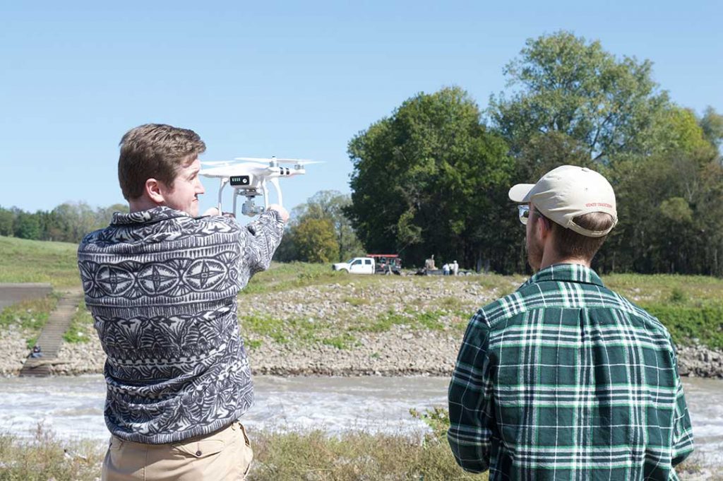 Jared Poland, left, and Jacob Meyers launch a drone for video of the Steele Bayou Control Structure while working on the Climate Change in Mississippi project.