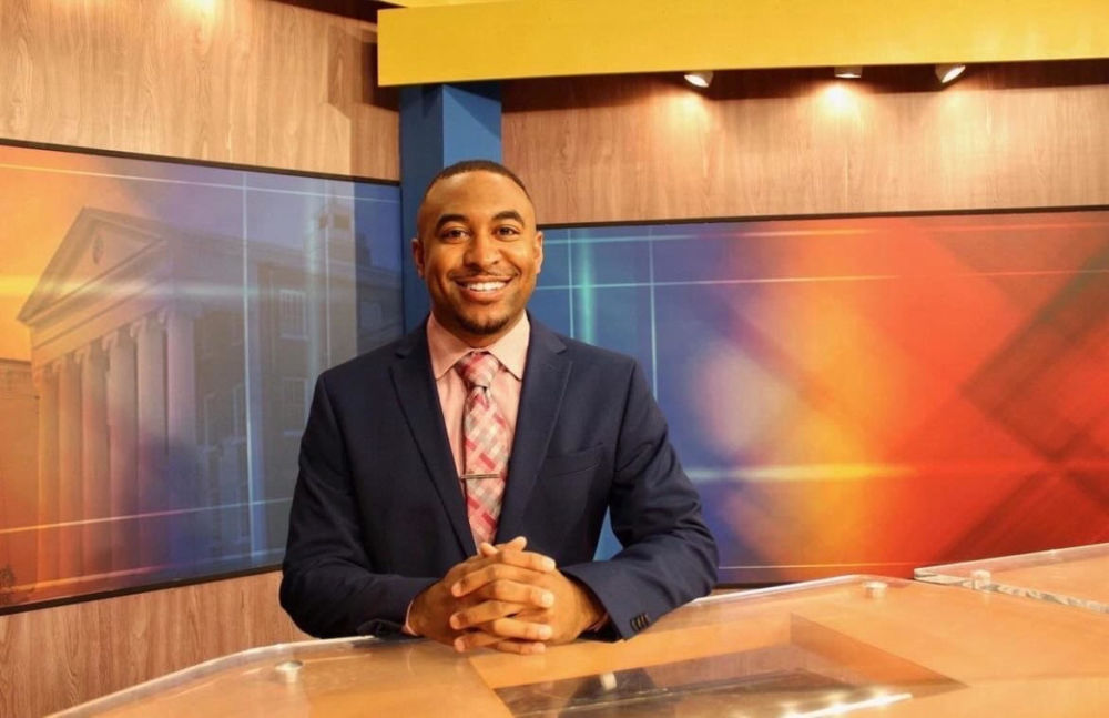 Student A.J. Norwood sits behind the anchor desk at NewsWatch.