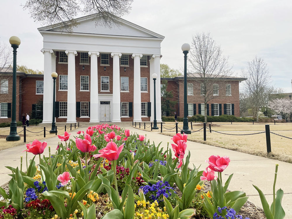 A picture of the Lyceum with colorful flowers in front of it in spring. Photo by Jodi Hallum.